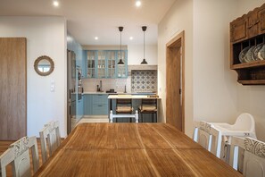 A dining area with a wooden table and chairs, a kitchen with blue cabinets, and pendant lights. - Close to all the magical places in Sintra. (Sintra)