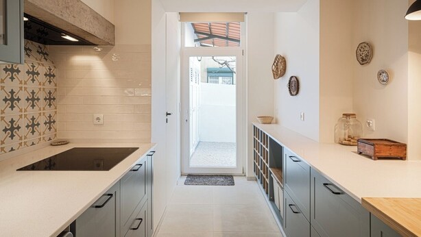 A modern kitchen with white cabinets, a black countertop, and a patterned backsplash. There is a view into the dining area through an open doorway. - Close to all the magical places in Sintra. (Sintra)