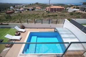 Une piscine sur le toit offrant une vue dégagée sur le paysage environnant, notamment sur les maisons et une colline.