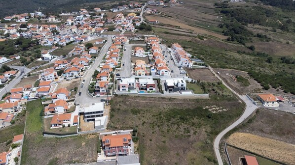 Vue aérienne d’un quartier résidentiel avec des maisons, des routes et des champs ouverts.