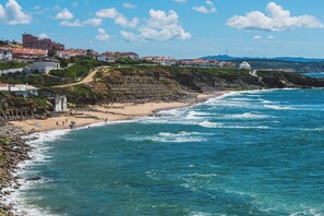 Une ville côtière avec des bâtiments construits le long de la falaise, une plage et l’océan.