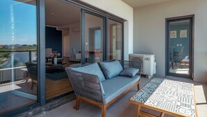 A balcony with a sofa, a table, and a view of the outdoors.