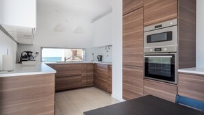 A modern kitchen with wooden cabinets, a black countertop, and stainless steel appliances including a microwave and oven.