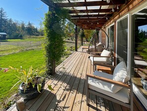 A wooden deck with a pergola, outdoor seating, and a view of a green landscape.