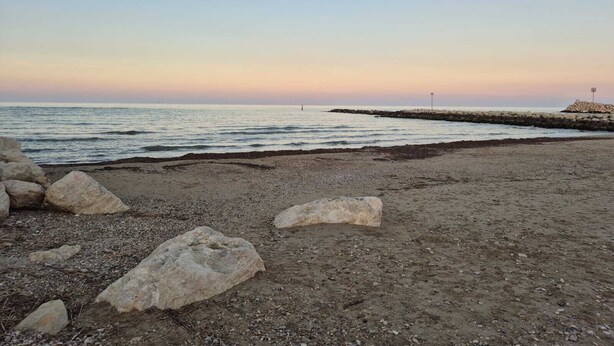 A beach with large rocks in the foreground and a rocky breakwater in the background. - Cozy apartment near the Sea with all amenities. (Citta Sant' Angelo)