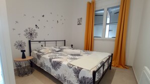 A bedroom with a bed, a bedside table, a window with curtains, and wall decorations. - Le MIMOSA des Cévennes, 10 minutes from La Bambouseraie, for a relaxing stay (Anduze)