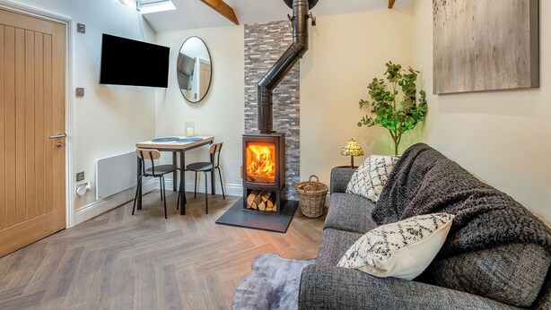 A cozy living room with a fireplace, wooden beams, a TV, and a dining area. - Rose Cottage - UK49048 (Banstead)