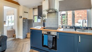 A modern kitchen with a built-in oven, a sink, and a window with a view of the outside. - Rose Cottage - UK49048 (Banstead)