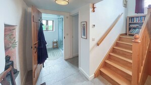 Eine Treppe führt zu einer Zwischenebene mit einem hölzernen Geländer und einem kleinen Holzschemel.