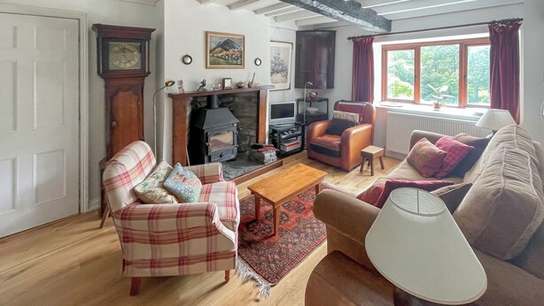 Ein gemütliches Wohnzimmer mit Kamin, Karo-Möbeln und Blick auf Grün.