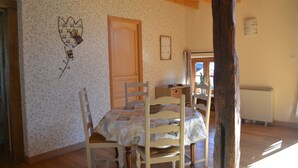 A room with a wooden ceiling, a bed with a floral-patterned bedspread, a wooden chair, a wooden table, and a wall with a floral wallpaper. - L'écrin du Val de Louyre, in the heart of Périgord Noir, with private pool (Val de Louyre et Caudeau)