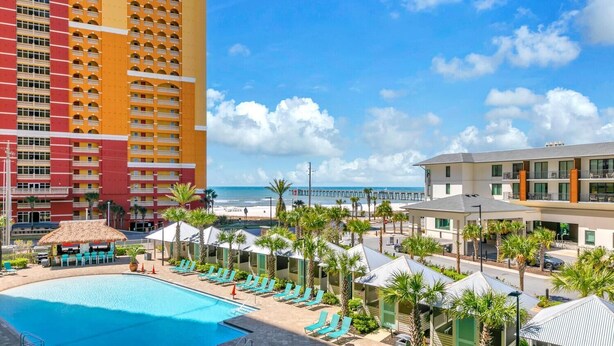 Ein Hotel mit Pool, Blick auf den Strand und einem Pier im Hintergrund.