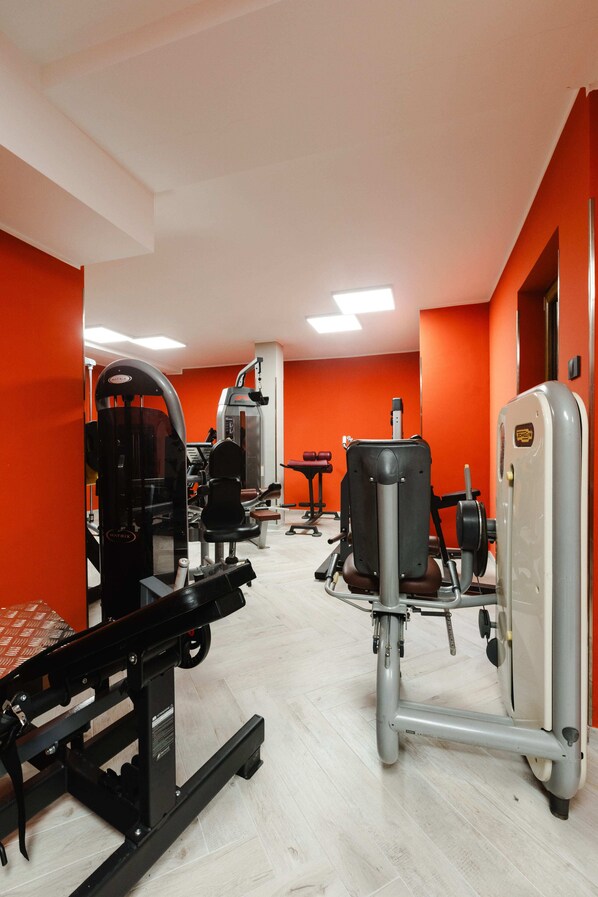 A gym with various exercise machines, a bench, and a weight bench.