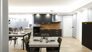 A modern kitchen with dark cabinets, a wooden countertop, and a dining area with a table set for four. - Villa Olivieri B&B - Wellness House  (Viterbo)