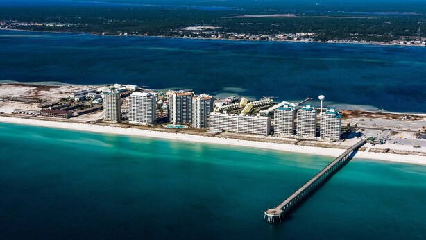 Un hotel costero con varios edificios altos, un muelle y una playa.