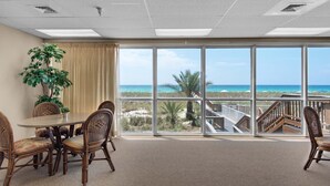 Un salón de conferencias con un amplio ventanal con vistas a la playa, una planta en maceta y una mesa de comedor con sillas.