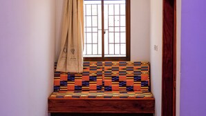 Une petite pièce avec un banc en bois, une fenêtre avec un rideau et une porte.