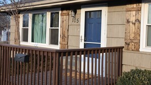 Una casa residencial con una puerta azul, el número 105, y un porche de madera.