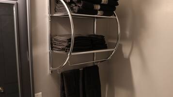 Een badkamer met een wit toilet, een handdoekrek met opgevouwen handdoeken en een spiegel boven het toilet.