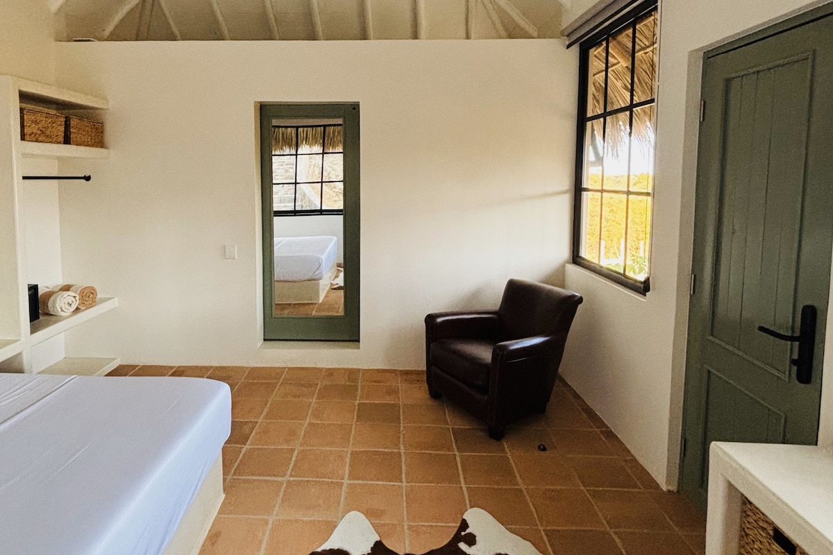 A room with a bed, a chair, a door, and a window.