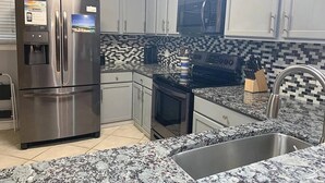 A modern kitchen with stainless steel appliances, a tiled backsplash, and granite countertops. - 11 Drift - 2BR $700+ in freebies incl golf, pool (Miramar Beach)