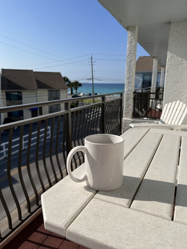 A white mug on a white outdoor table with a view of the ocean and buildings in the background. - 11 Drift - 2BR $700+ in freebies incl golf, pool (Miramar Beach)