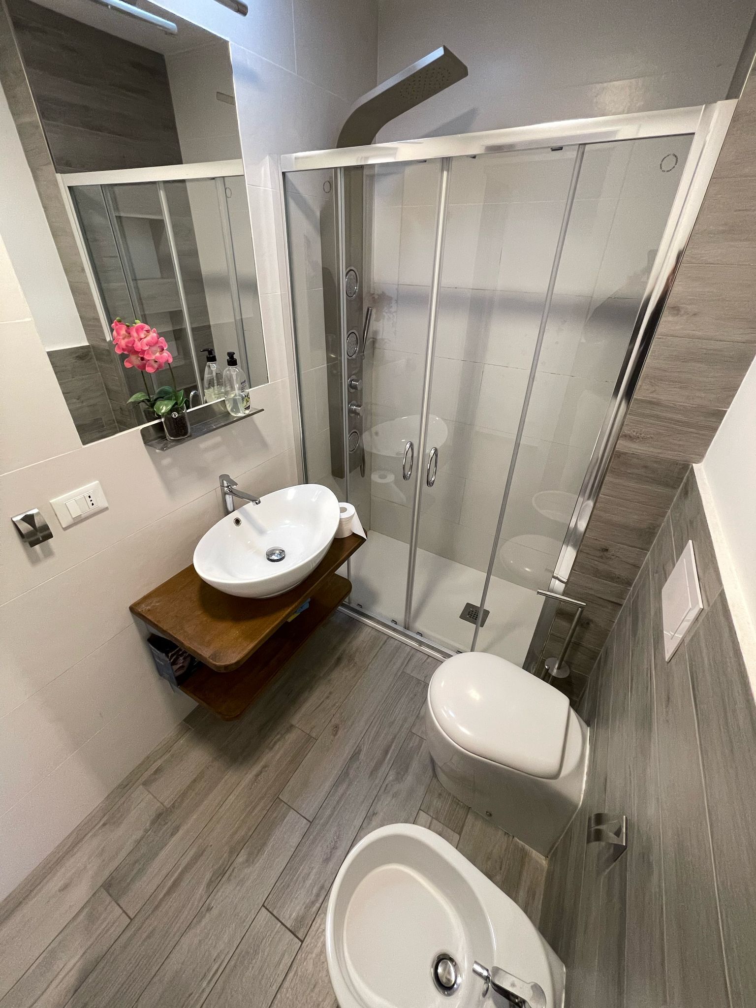 Une salle de bain moderne avec une douche à parois de verre, un lavabo sur colonne et des toilettes.