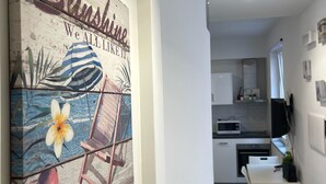 A modern kitchen with white cabinets, a microwave, and a dining area with a white table and chairs. - Macallè House Letojanni - Taormina (Letojanni)