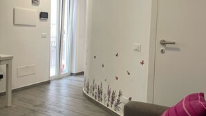 A modern living room with a grey sofa, a pink pillow, and a wall decorated with butterfly decals. - Macallè House Letojanni - Taormina (Letojanni)