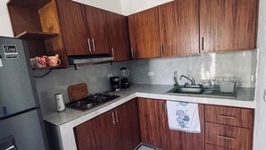 Una cucina compatta con mobili in legno, un fornello a gas, un lavello e un frigorifero.