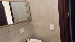 Un bagno con un lavabo bianco su piedistallo, uno specchio con cornice dorata e una porta in legno.