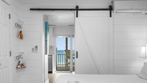 Et soveværelse med seng, ventilator, havudsigt og dør til en balkon.