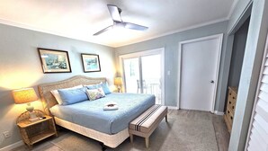 Een slaapkamer met een bed, nachtkastjes, een plafondventilator en een deur die uitkomt op een balkon.