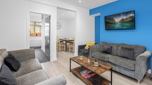A modern living room with a grey sofa, a wooden coffee table, and a blue accent wall.