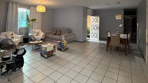 A spacious living room with a tiled floor, a sofa set, a coffee table, and a drum set.