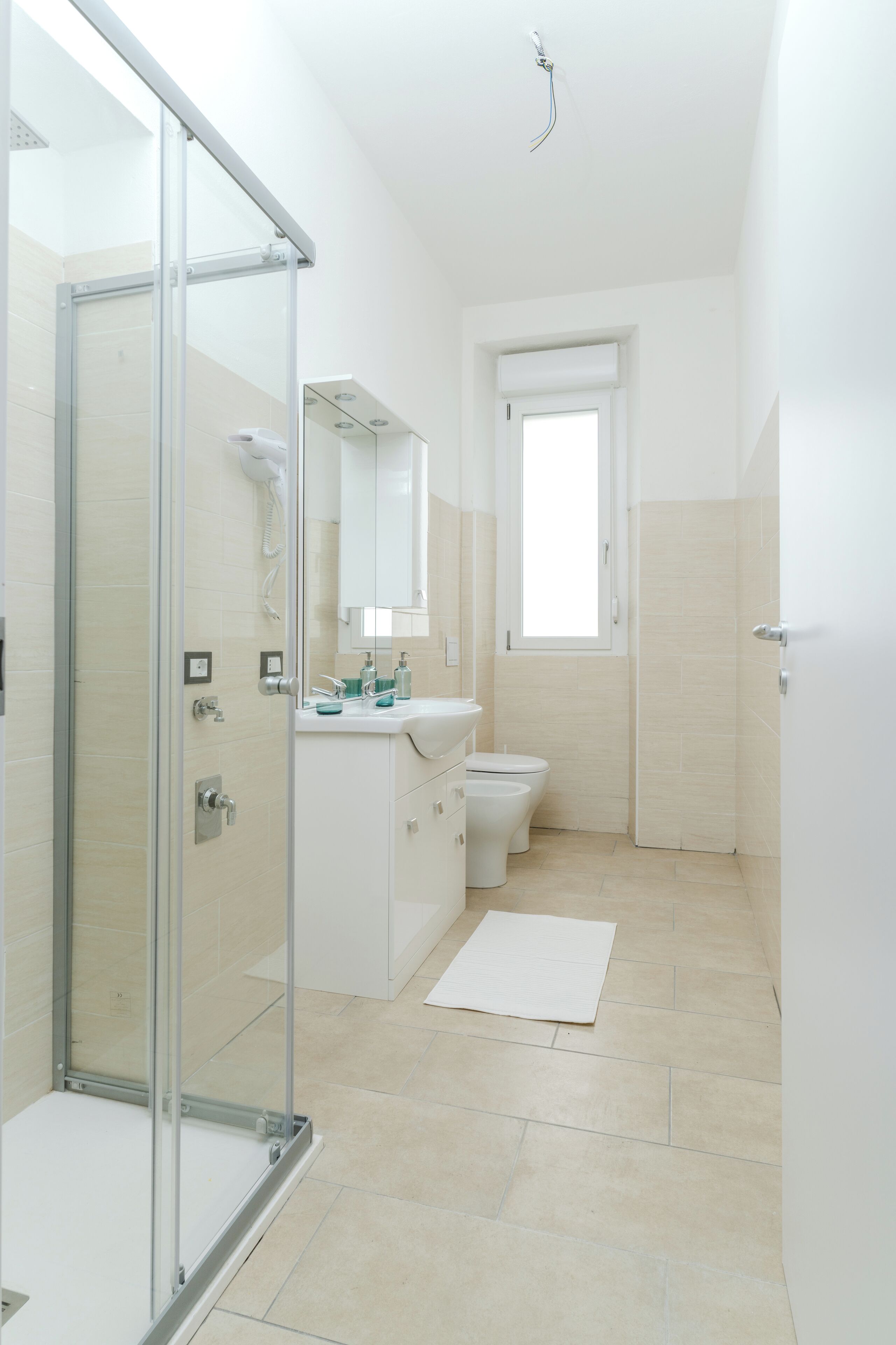 A modern bathroom with a glass shower enclosure, a sink with a mirror, and a toilet.
