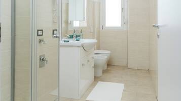 A modern bathroom with a glass shower enclosure, a sink with a mirror, and a toilet.