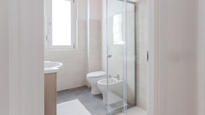 A modern bathroom with a glass shower enclosure, a toilet, and a sink.