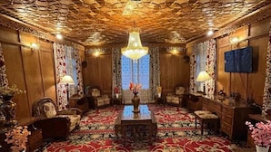 A room with a patterned carpet, wooden furniture, a chandelier, and a ceiling fan. - New Alzira Heritage Group of Houseboats  (Srinagar)