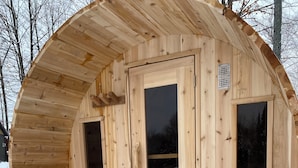 A wooden sauna with a circular design, featuring two benches and a central door.