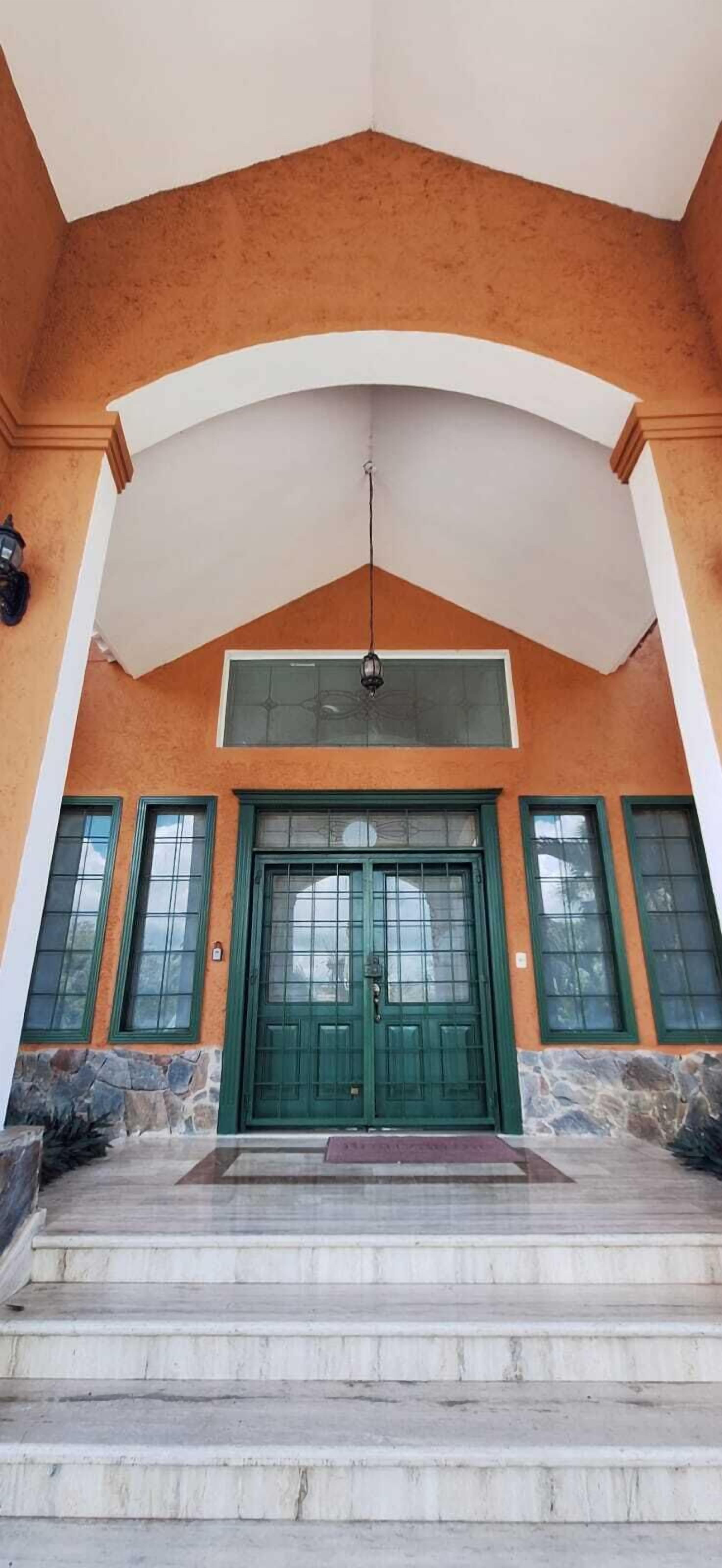 A building entrance with a green door, stone steps, and a white archway.
