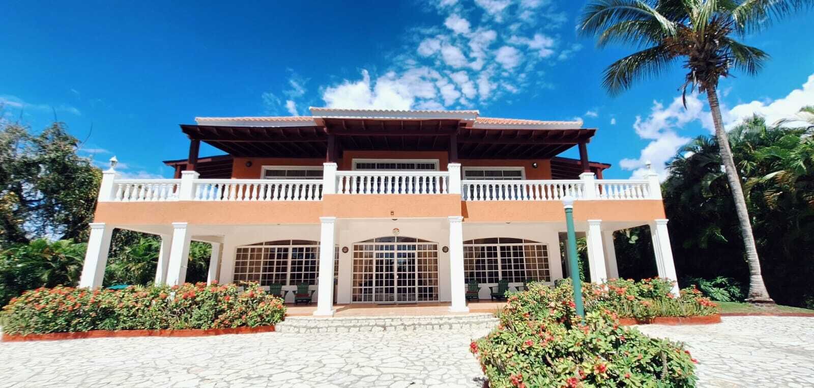 A two-story building with a balcony, large windows, and a stone-paved entrance.