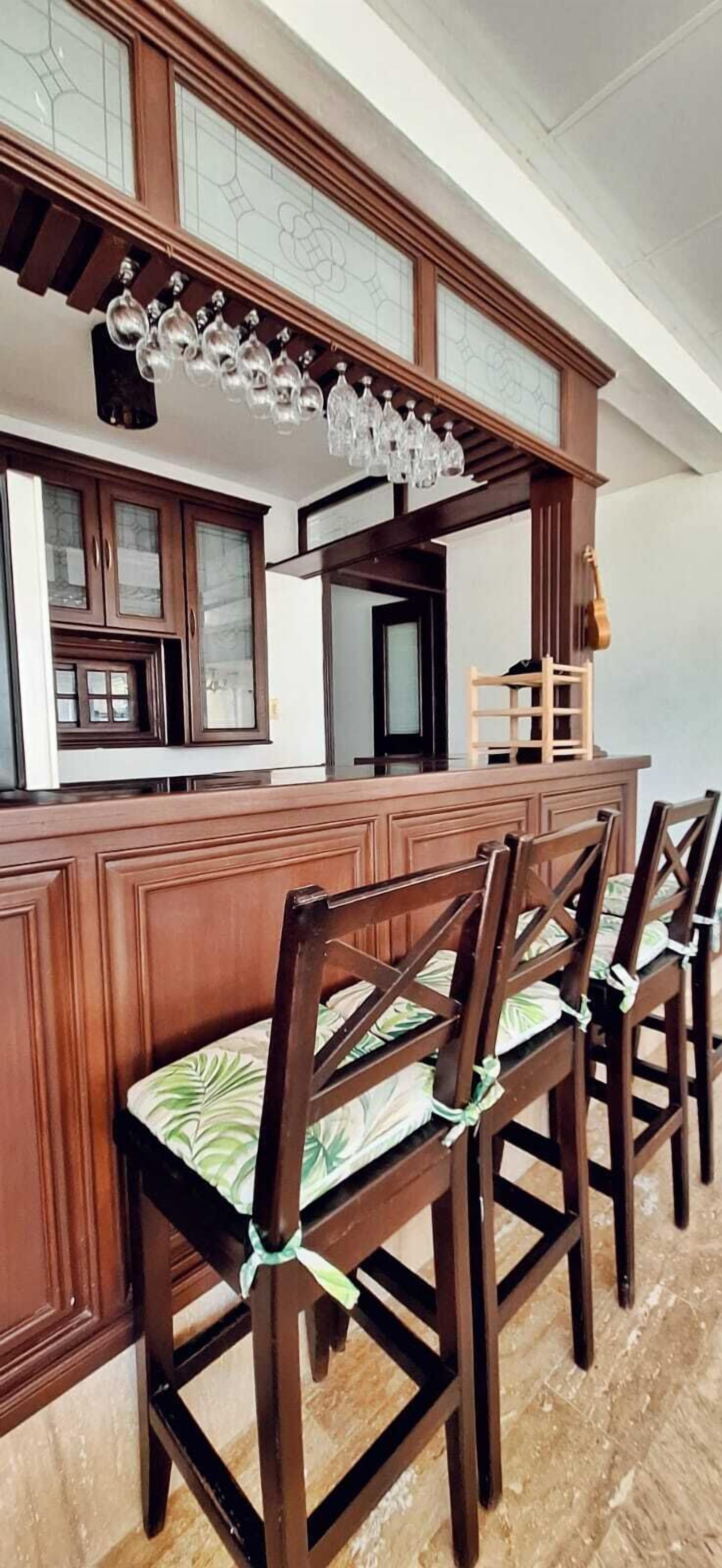 A bar area with wooden bar stools and a hanging light fixture.