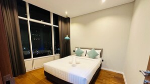 Una habitación de hotel con un ventanal grande, una cama con almohadas y suelo de madera.