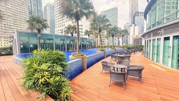 A rooftop terrace with a pool, seating area, and modern buildings in the background.