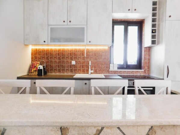 Una cocina moderna con armarios blancos, salpicadero de azulejos y una ventana.