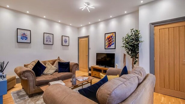 A modern living room with two sofas, a coffee table, a TV, and framed artwork on the walls. - Cosy Walkers Retreat in Meltham Doggie Friendly (Holmfirth)
