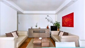 A modern living room with two sofas, a coffee table, a TV, and a red abstract painting. - The Poet - Bright and Spacious by Mon Petit Faré (Paris)