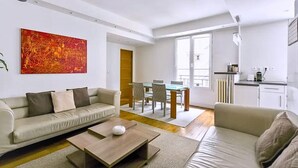 A modern living room with a sofa, coffee table, and a dining area with chairs and a table. - The Poet - Bright and Spacious by Mon Petit Faré (Paris)