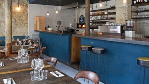 A restaurant interior with wooden tables and chairs, a bar area, and a stone wall. - The Poet - Bright and Spacious by Mon Petit Faré (Paris)